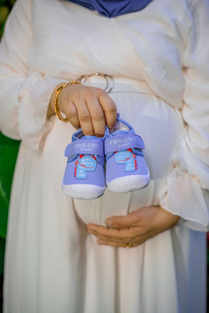 Mother-to-be holding tiny baby shoes over her bump