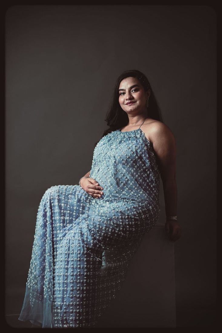 Mother-to-be smiling in a blue dress in the studio