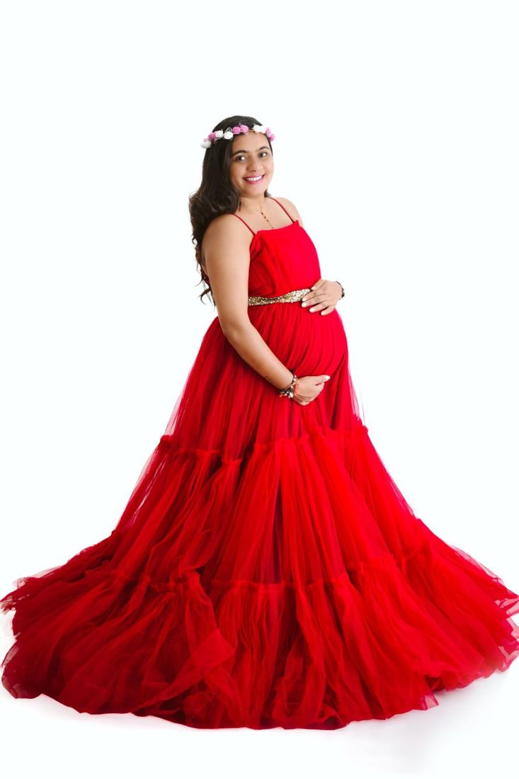 Smiling mother-to-be in a flowing red gown