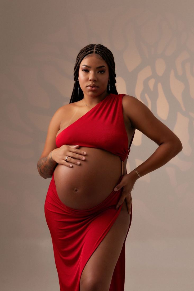 Mother-to-be in a red gown in a studio portrait
